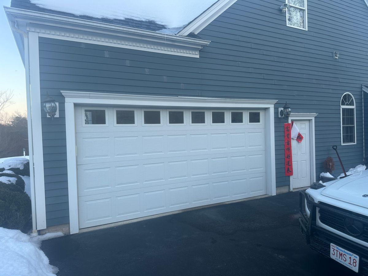White garage door with decorative windows on blue colonial home — winter in MA